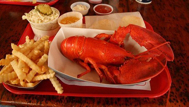 A meal of boiled lobster with fries on a red tray. 